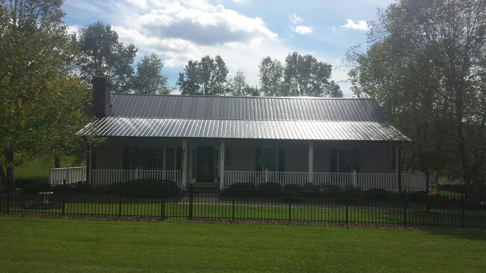 Gray metal roof on a brick ranch with a full width front porch — Gutter Guard Installation work by our crew in Delafield