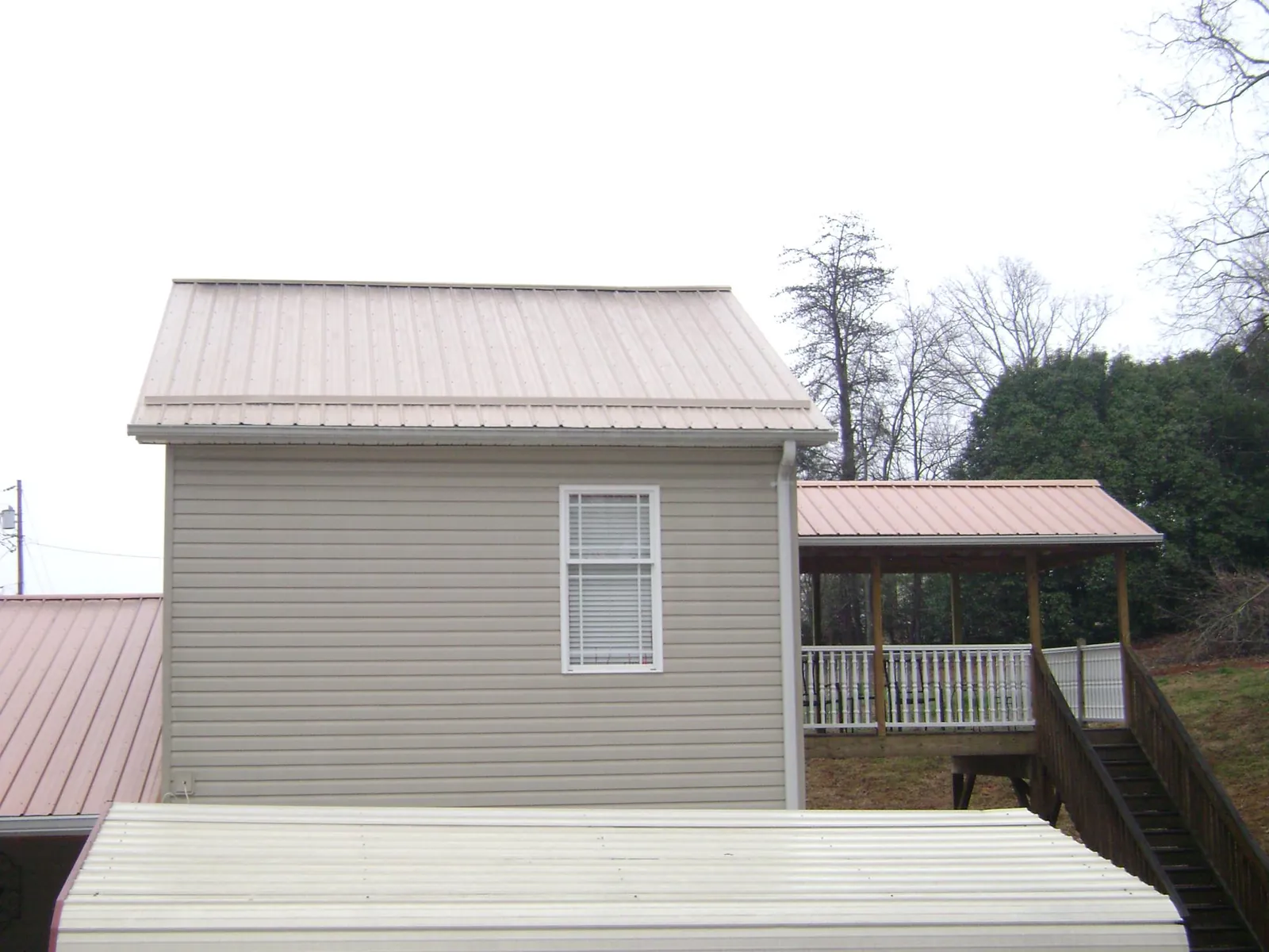 Tan metal roofs on a two story addition and attached porch, from a Roof Replacement job in Delafield