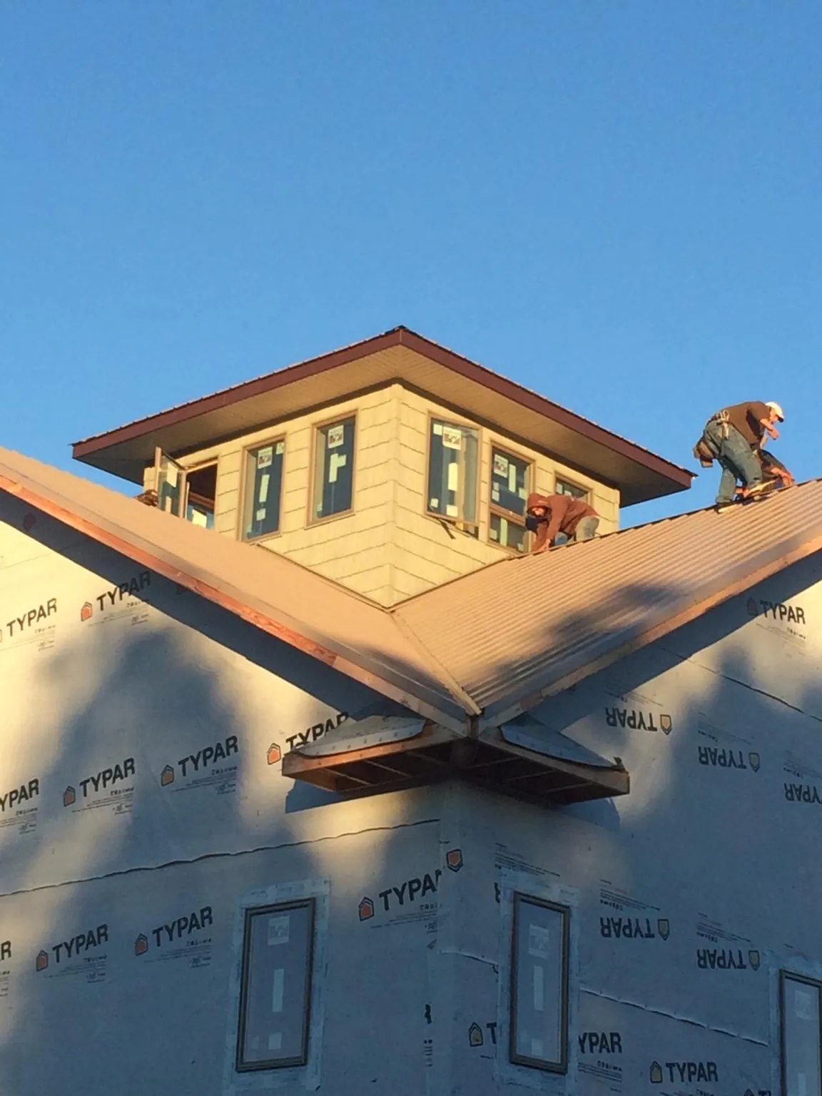 Roofers working around a rooftop cupola on a new metal roof at sunset — Roof Waterproofing in Delafield by Roofing Brothers